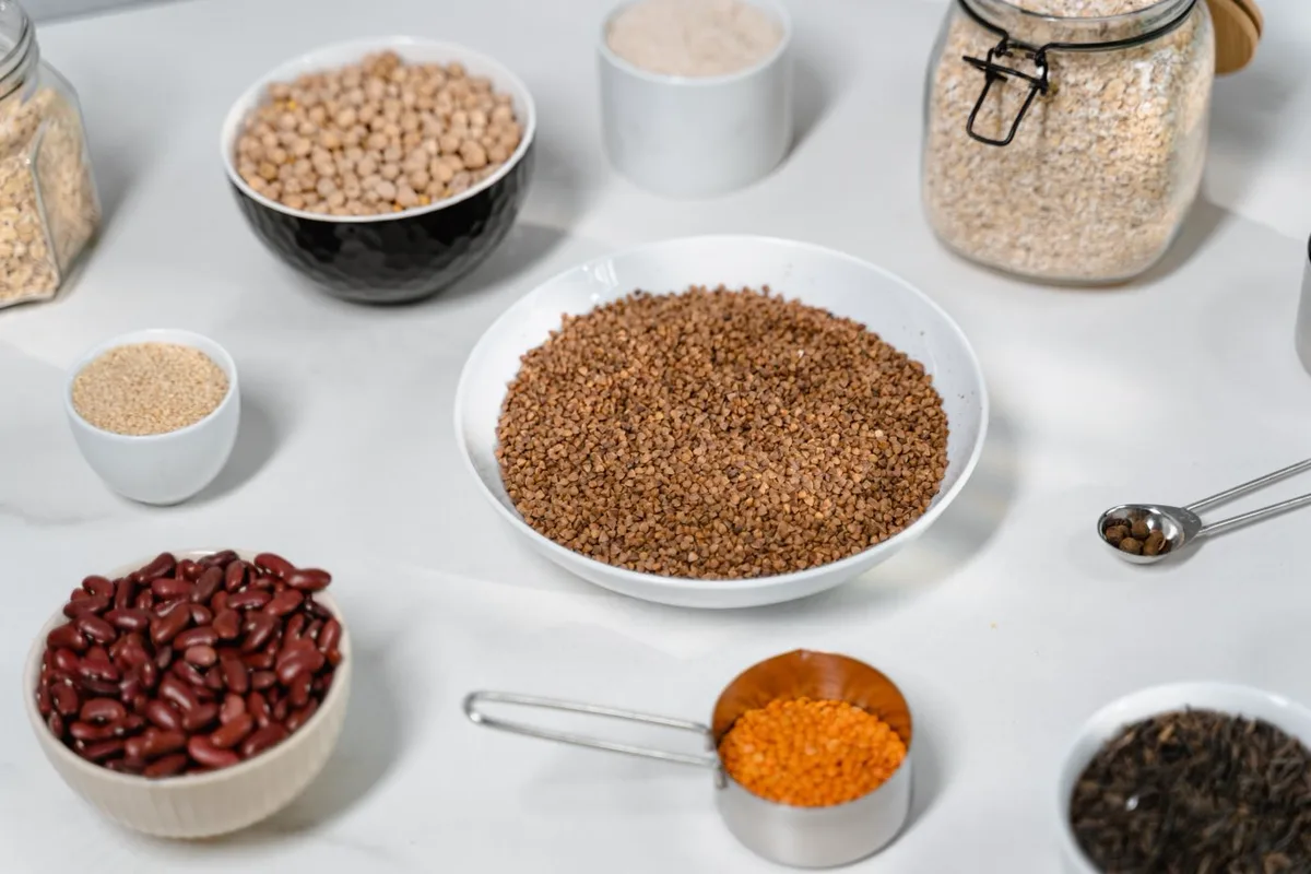 Bowls of chickpeas, kidney beans, lentils and whole grains arranged on a white kitchen counter